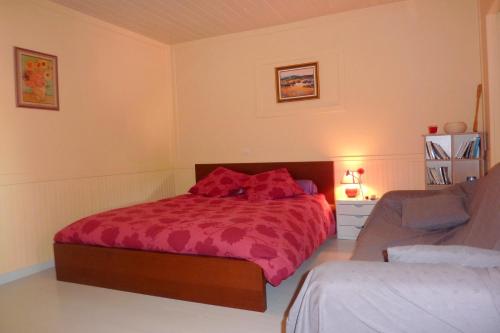 Chez Gillou في Boën: غرفة نوم مع سرير مع لحاف احمر