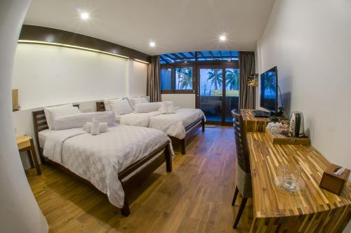 a hotel room with two beds and a television at Baantalay Thungwualaen in Pathiu