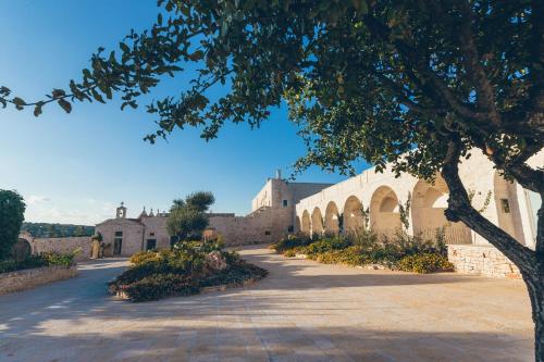 a building with a tree in the middle of a road at Masseria Grieco in Ostuni