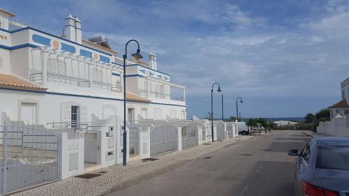 a white building with a fence next to a street at Villa Lota in Vila Nova De Cacela