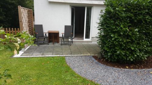 a patio with two chairs and a table next to a bush at Ferienwohnung Jürgens in Rheinbreitbach