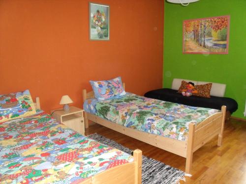 two beds in a room with green and orange walls at Viola Vendégház in Kehidakustány