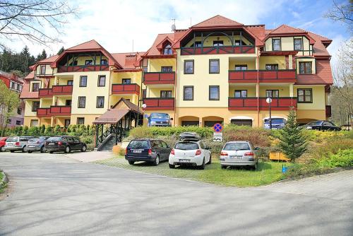 a large building with cars parked in front of it at Parkowa Polana MyWeek in Polanica-Zdrój