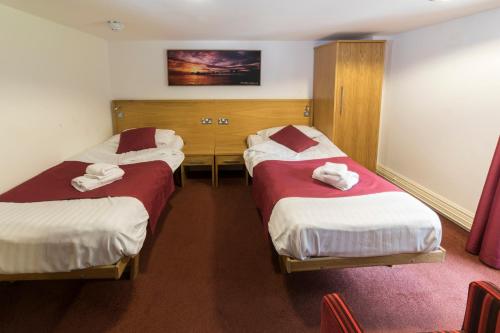 two beds in a hotel room with towels on them at Plas y Brenin - National Outdoor Centre in Capel-Curig