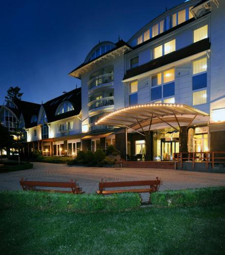 two benches in front of a building at night at MenDan Magic Spa & Wellness Hotel in Zalakaros