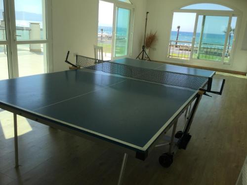a ping pong table with a net in a room at Aphrodite Beachfront Apartment in Ghaziveran