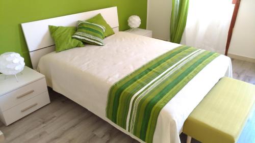 una camera da letto con un letto bianco con una coperta verde e gialla di B&B Micucco a Milazzo
