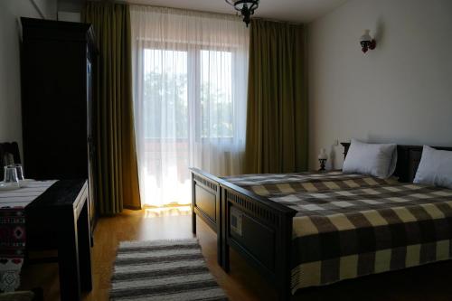 a bedroom with a large bed and a large window at Pensiunea Casa Bunicului in Mociu