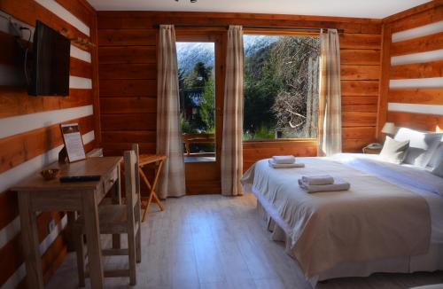 a bedroom with a bed and a desk and a window at Casa del Lago Villa La Angostura in Villa La Angostura