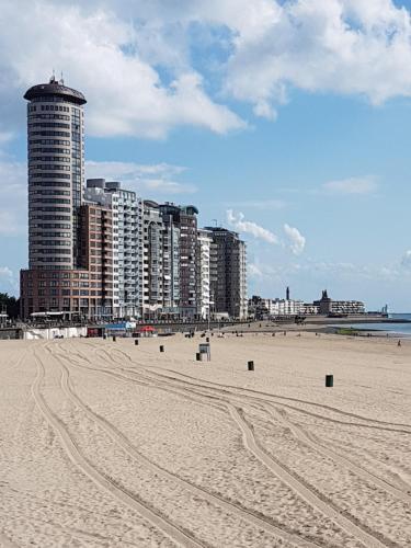 einen Strand mit hohen Gebäuden und Fußabdrücken im Sand in der Unterkunft Stad & Strandhotel Elisabeth in Vlissingen
