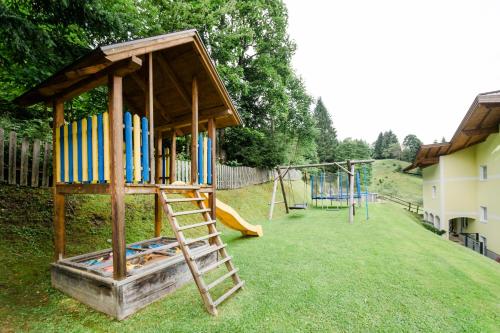 a playground with a wooden play structure and a slide at 4 Mountains Apartments in Kleinarl