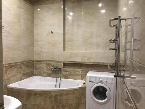a bathroom with a tub and a washing machine at Apartments on Rudanskogo in Kyiv
