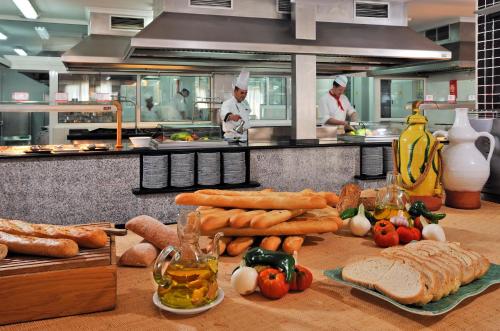two chefs in a kitchen with bread and vegetables at Sol Milanos Pingüinos in Son Bou