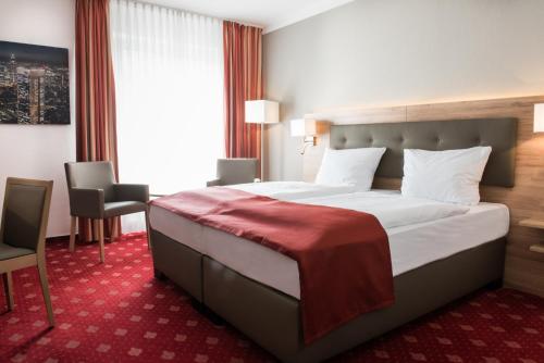 a hotel room with a large bed with a red carpet at Hotel Novostar in Göttingen