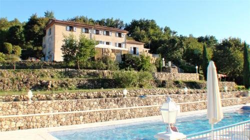 a pool in front of a house with an umbrella at B&B with charm, quiet, kitchen, sw pool. in Grasse