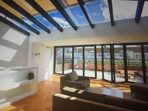 sala de estar con sofá y ventanas grandes en Fantastic Bright Penthouse, en Ámsterdam