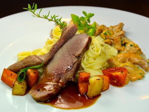 a white plate of food with sausage and pasta at Genusshotel Hirschen - Erholung im Grünen (Südschwarzwald) in Sallneck