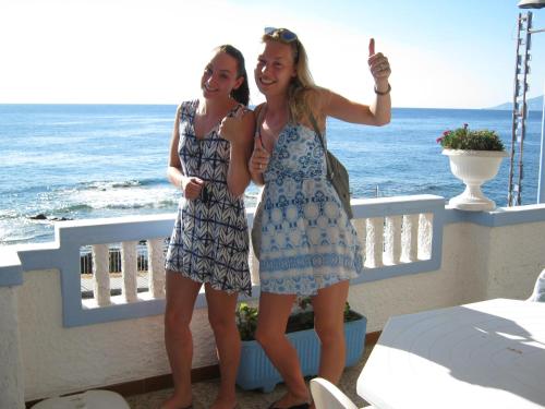 two women in dresses standing on a balcony with the ocean at B&B AcquaDolce in Cala Gonone