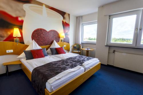 a hotel room with a bed with a heart on the wall at Hotel Rheingold in Gernsheim