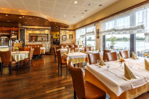 a dining room with tables and chairs and windows at Hotel Rheingold in Gernsheim