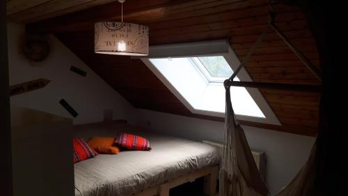 een kamer met een bed op een zolder met een raam bij La Masure in Érezée