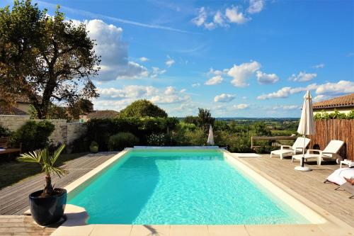 a swimming pool in a backyard with a deck and chairs at L'Ancienne Forge 27 rue de la Crèche Bourg Born in Villeréal