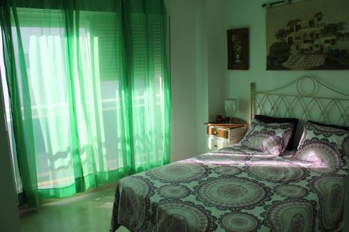 Un dormitorio con una cama con cortinas verdes. en Atico Costa Ballena golf y playa parking&wifi, en Costa Ballena