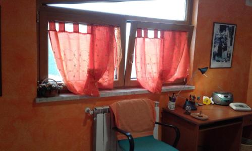 a desk with a chair and a window with red curtains at B&B Villa Milena in Ariano Irpino