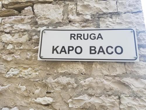 a white street sign on a stone wall at Lori's traditional house in Gjirokastër