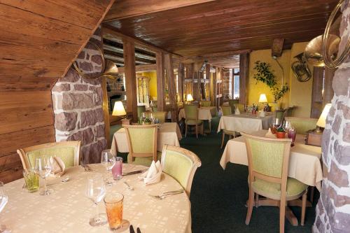 a restaurant with tables and chairs and a stone wall at Auberge La Meuniere in Thannenkirch