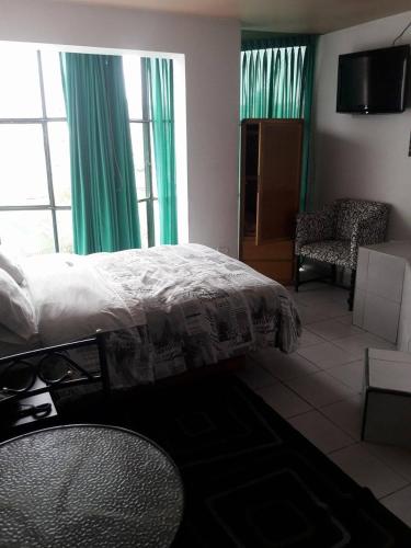 a bedroom with a bed and a chair and window at CasaHotel Jockey Plaza Mall in Lima