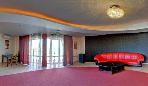a living room with a red couch and a table at Tsentralniy Hotel in Khmelʼnytsʼkyy