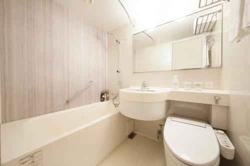 a white bathroom with a toilet and a sink at Richmond Hotel Naha Kumoji in Naha