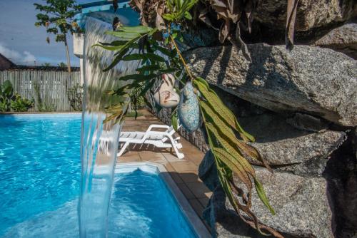 una piscina con una estatua junto a una pared de roca en Pousada Canoeiros, en Arraial d'Ajuda