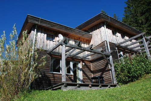 a log cabin with a porch and a chair in front at Feriendorf Tauerngast in Hohentauern