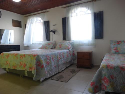 a bedroom with two beds and two windows at Casa Pontal Ilheus in Ilhéus