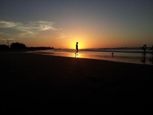 a person walking on the beach at sunset at Casa Dos Patos in Flecheiras