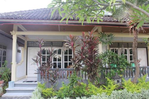 a white house with palm trees in front of it at Taman Lily's Hotel in Lovina