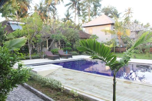 a pool in a yard with two chairs and a house at Taman Lily's Hotel in Lovina
