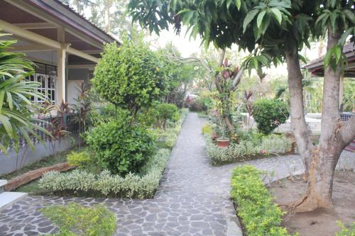a garden with trees and plants and a walkway at Taman Lily's Hotel in Lovina