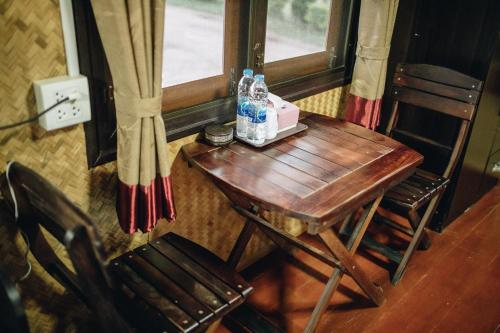 a wooden table with two bottles of water and two chairs at Phoomtada Homestay in Wiang Pa Pao