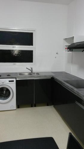 a kitchen with a sink and a washing machine at Le Rêve Bleu in Dumbéa