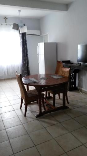 a kitchen with a table and chairs and a refrigerator at Le Rêve Bleu in Dumbéa