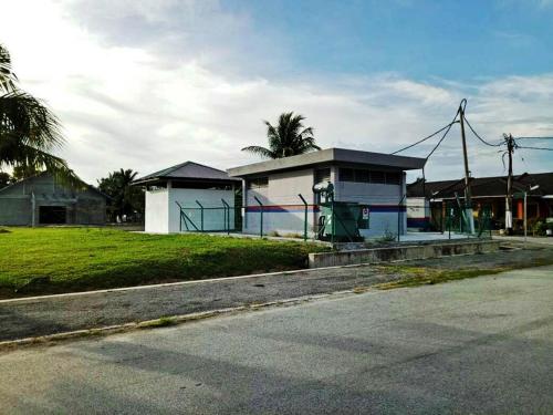a building with a fence next to a street at Farzai Homestay in Lumut