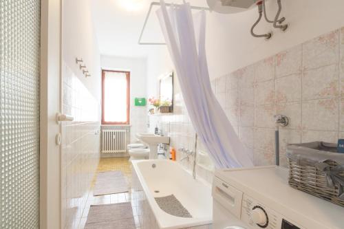 Baño blanco con bañera y lavamanos en Bilocale centro Biella, en Biella