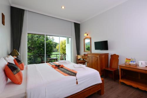 a bedroom with a white bed and a large window at Princess River Kwai Hotel in Kanchanaburi