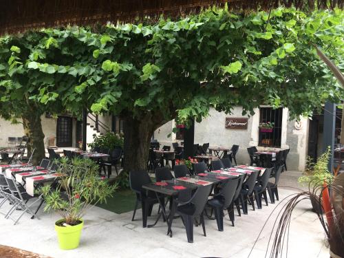 a group of tables and chairs under a tree at Le Relais Des Vieilles Postes in Les Avenières