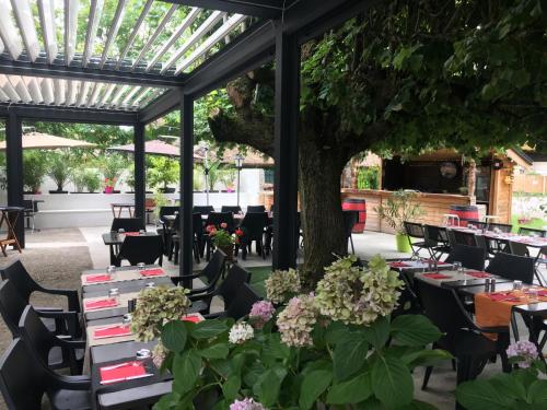 a dining room with tables and chairs and a tree at Le Relais Des Vieilles Postes in Les Avenières