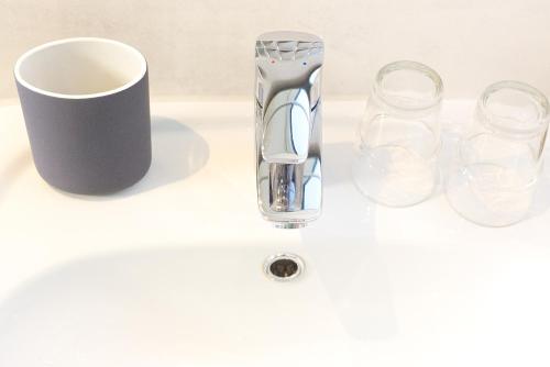 a white sink with a vase and glasses on it at Pfannkuchenhaus Fehmarn in Burg auf Fehmarn