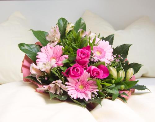 a bouquet of pink flowers on a bed at Pfannkuchenhaus Fehmarn in Burg auf Fehmarn